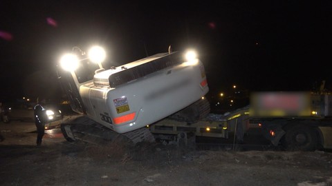 Deprem bölgesine giden TIR'ın taşıdığı iş makinesi yola devrildi
